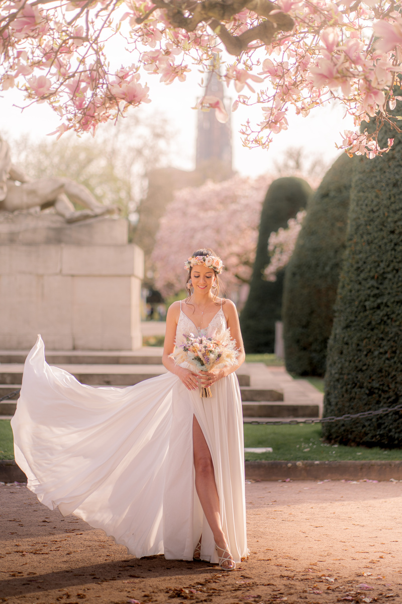 portrait de la mariée avec robe qui vole au vent sous les magnolias en fleurs